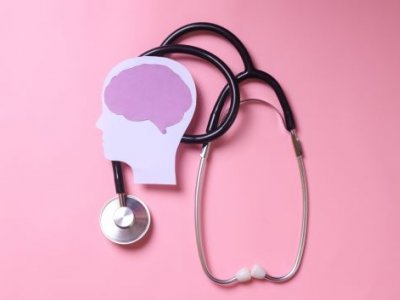 Stethoscope and stylised human head and brain on pink background.