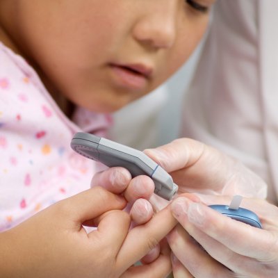 A child has a finger prick test for blood sugar levels