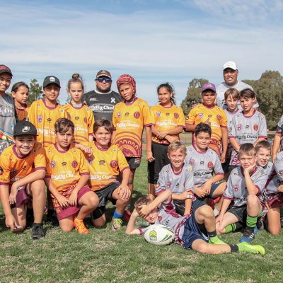 A group of young Aboriginal and Torres Strait Islander boys pose in yellow rugby uniforms. They are smiling.