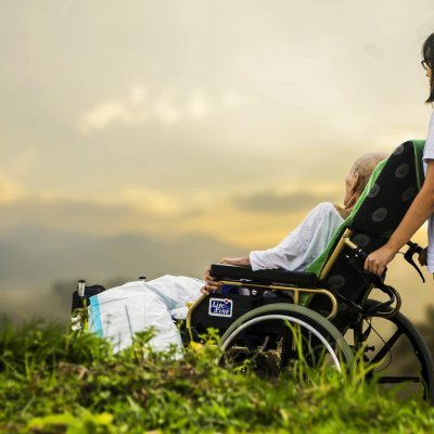 A carer with an elderly patient look at the sunset.