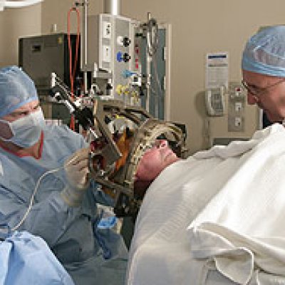 Professor of Clinical Neuroscience, Peter Silburn (right) talks with a patient about to undergo deep brain stimulation, as neurosurgeon, Dr Terry Coyne, implants the microelectrodes that will deliver the treatment.