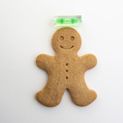 A gingerbread man underneath a spirit level.