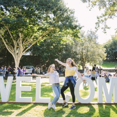 Students at UQ in front of a Welcome sign.