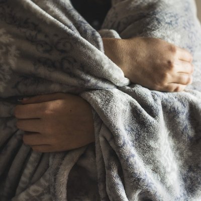 Man holding blanket around his upper body