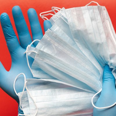 hand wearing surgical gloves and holding face masks