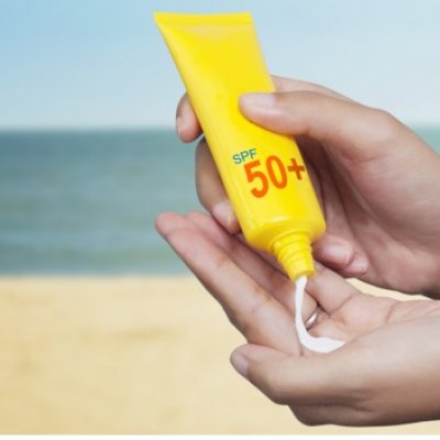 Pair of hands holding a tube of sunscreen, and squeezing some into one palm