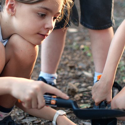 A young girl digs in the dirt to fill a Soils for Science sample bag.