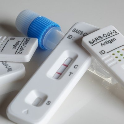 Used rapid antigen tests in a pile show positive and negative results.