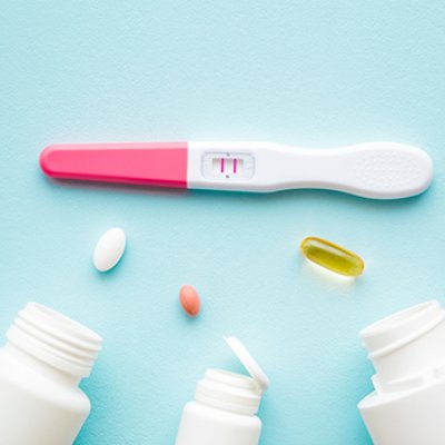 A positive pregnancy test with three pill bottles laying on their sides