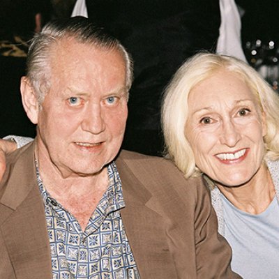 Chuck and Helga Feeney sitting down and smiling. Helga has her arm across Chuck's shoulders.