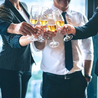 A group of people dressed in corporate wear clinking champagne glasses
