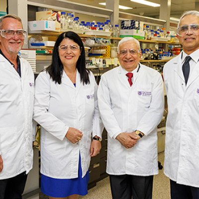 Four smiling people wearing safety equipment in a laboratory