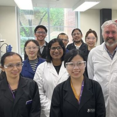 A group of people standing in a laboratory wearing white lab coats.