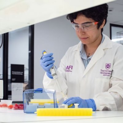 A woman wearing a lab coat doing an experiment in a science lab.