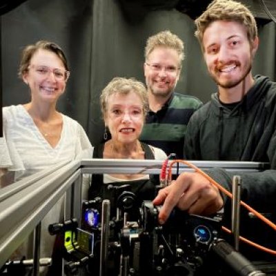 Two women and two men stand behind computer equipment