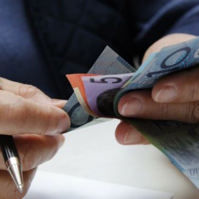 Close up of hands holding Australian dollar notes.