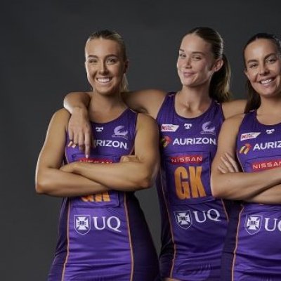 3 Firebirds players dressed in their purple netball uniforms smiling.