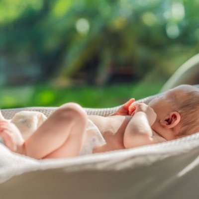 Newborn baby lying on bed in the sunlight.