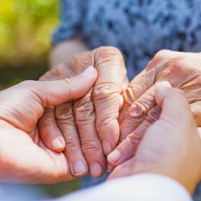 A person clasps hands with an elderly person