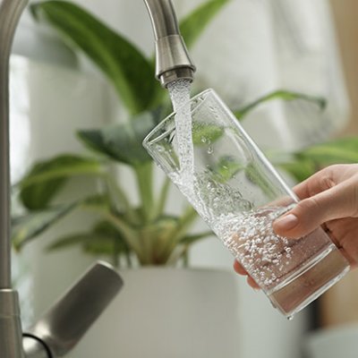 Person filling glass with water from tap. Adobe