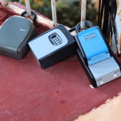 Three key boxes attached to a gate at a holiday rental complex