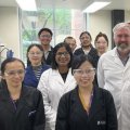 A group of people standing in a laboratory wearing white lab coats.