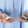 Person holding cigarettes in one hand and a vape in the other