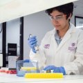 A woman wearing a lab coat doing an experiment in a science lab.