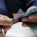 Close up of hands holding Australian dollar notes.