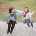A boy and a girl swinging on swings