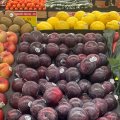 a tray of plums among other fruit in a supermarket
