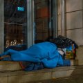 A homeless man asleep on the sidewalk
