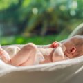 Newborn baby lying on bed in the sunlight.