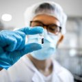 A man in a laboratory holds a vial up to his face