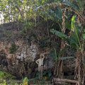 a man stands in front of a large rock holding a measuring tape