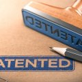 A close up of a blue stamp with the word 'patented' stamped on a brown folder. 