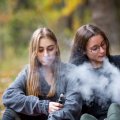 Two young women using vapes outdoors. Image, Adobe.