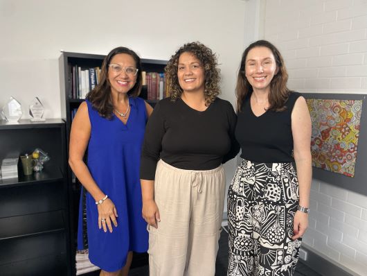 Three women standing and smiling at the camera 
