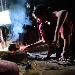 A young girl cooking over an open flame