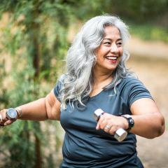 Woman holding weights while exercising outside 