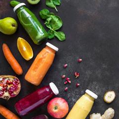 Fruits and vegetables surrounded by bottles of juices and smoothies