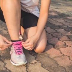 A woman ties her shoelace prior to exercise