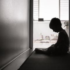 A child sitting in a hall way with its head down.