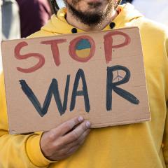 A protested with a sign that says stop war, relating to Russia's invasion of Ukraine