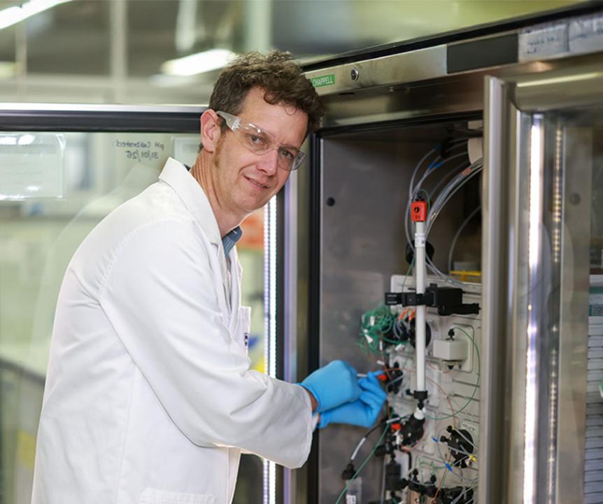 Professor Keith Chappell in white lab coat and blue gloves.