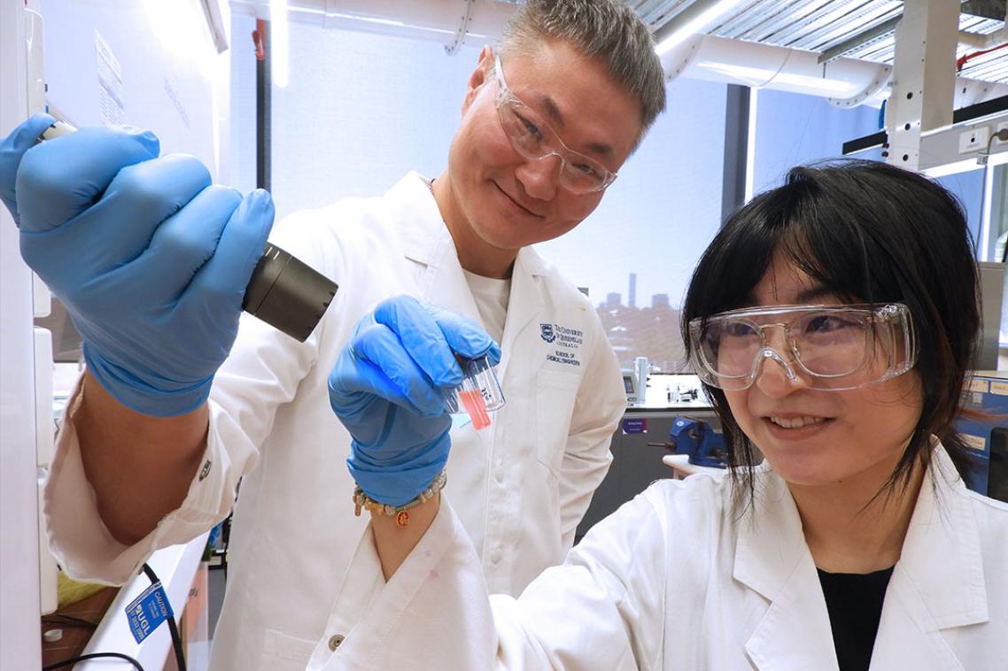 Two scientists in lab coats holding a UV light technology 