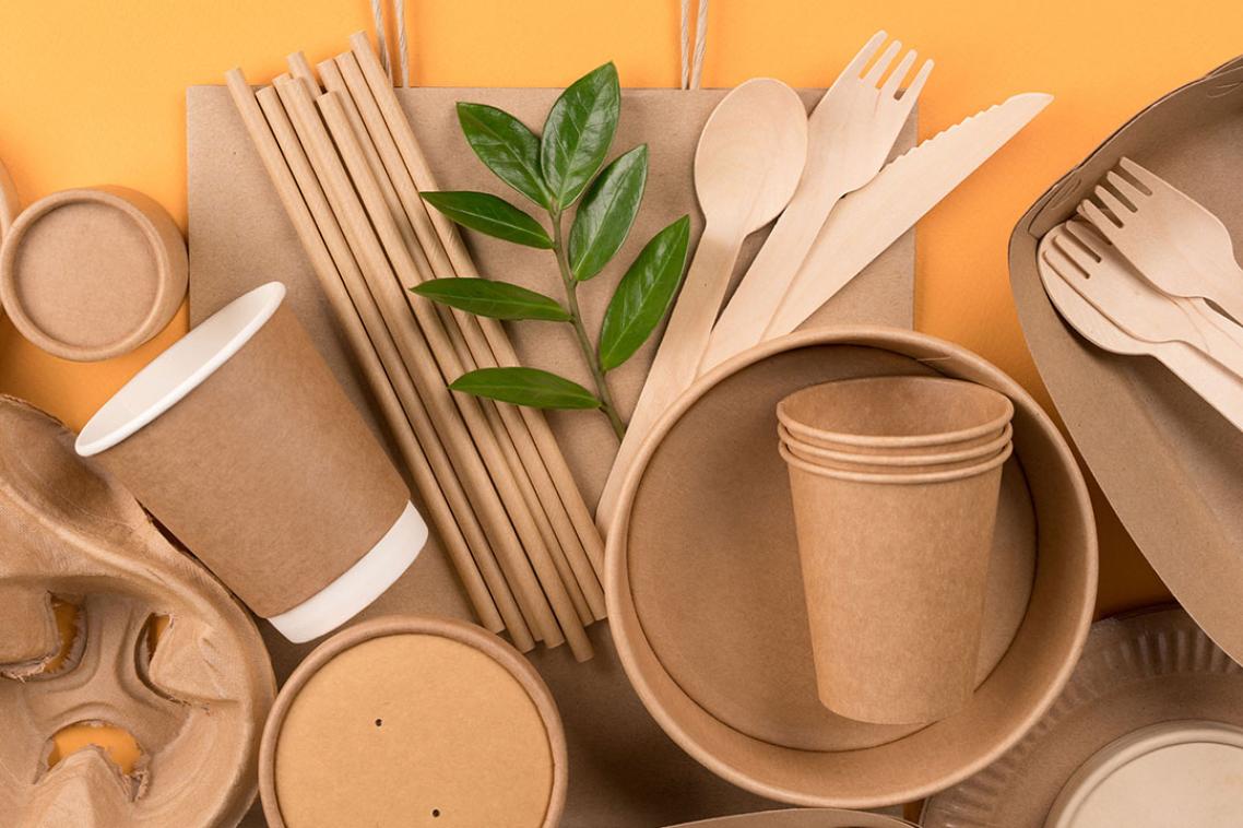 cardboard food packaging including forks, knives, bowls and plates on an orange background