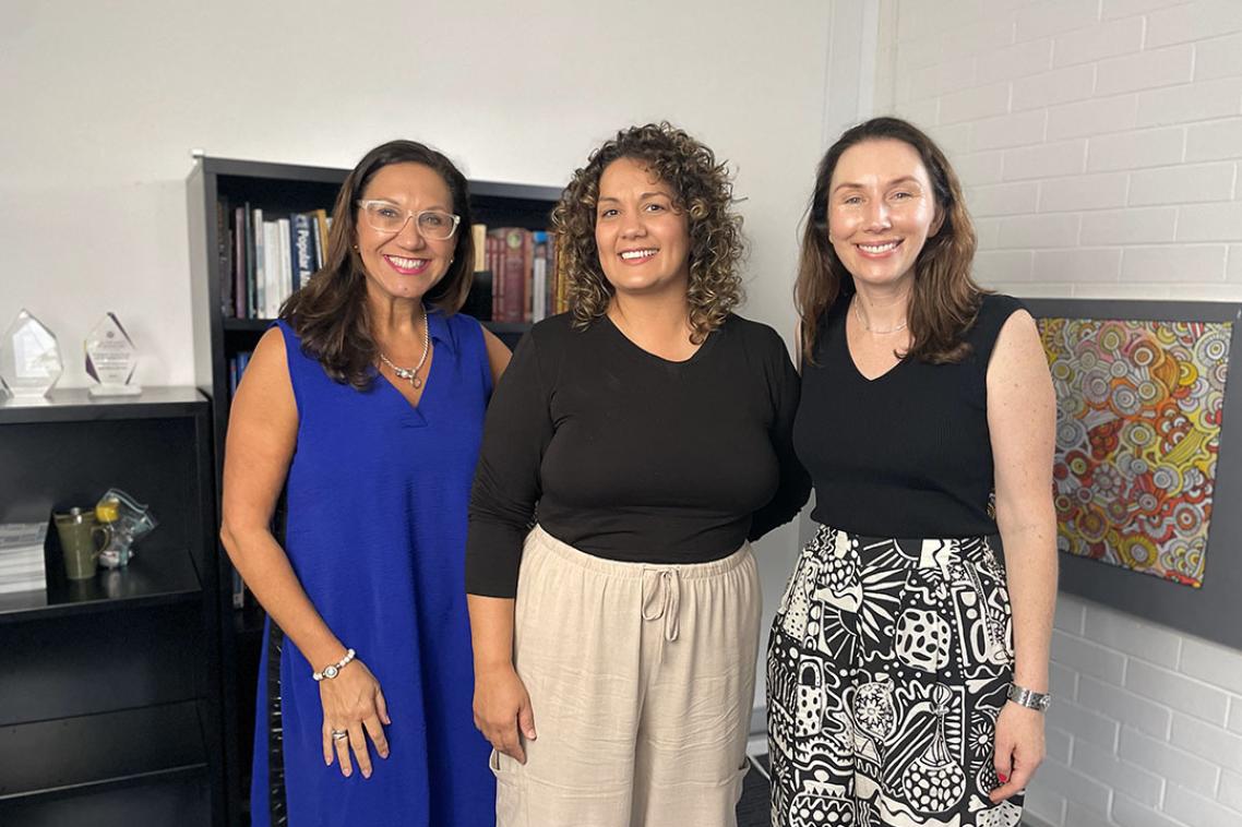 Three women standing in a row smiling at the camera