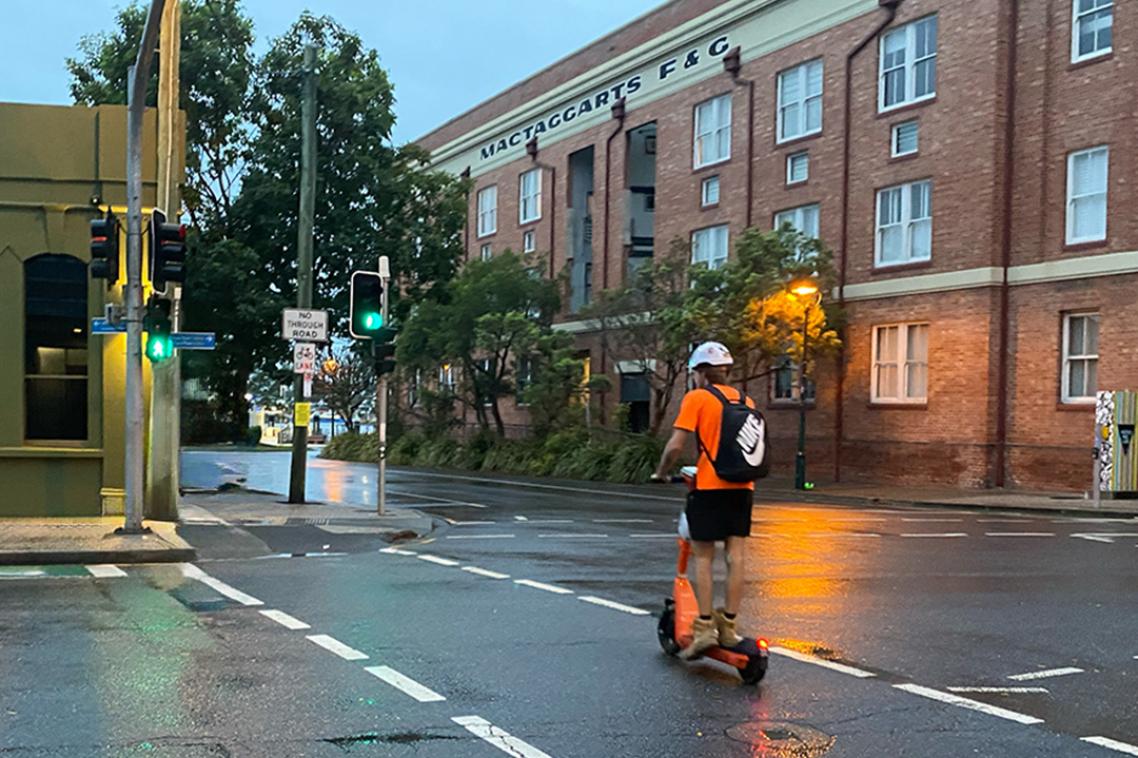 A man on a electric scooter riding down the street