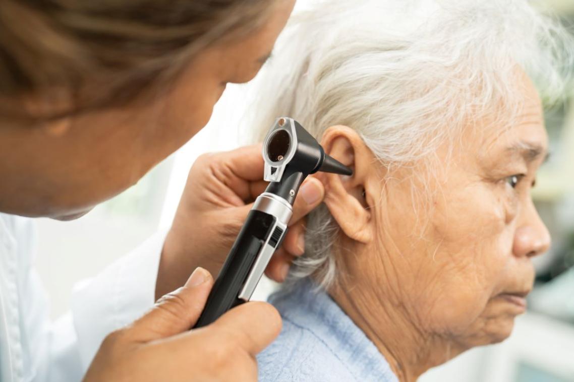 An audiologist using a device to look into an elderly persons ear